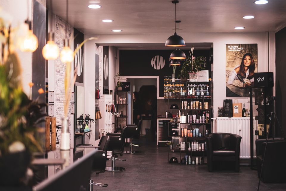 Blick in den Salon mit schwarzen Bedienstühlen, Produktregal und KW-Logo an der Wand