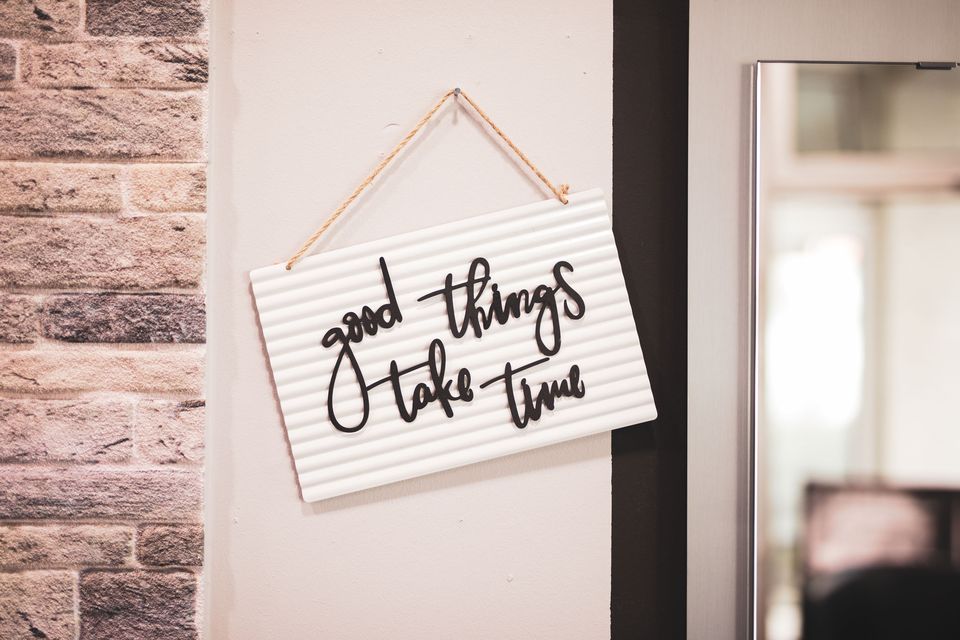 Schild mit dem Schriftzug „good things take time“ an der Salonwand